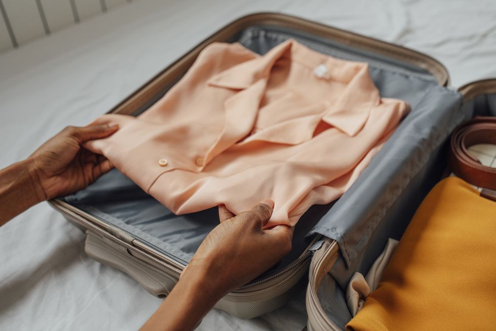 Woman putting silk blouse in a suitcase
