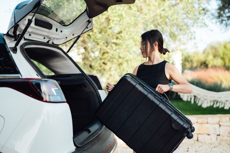 Woman putting suitcase in the car
