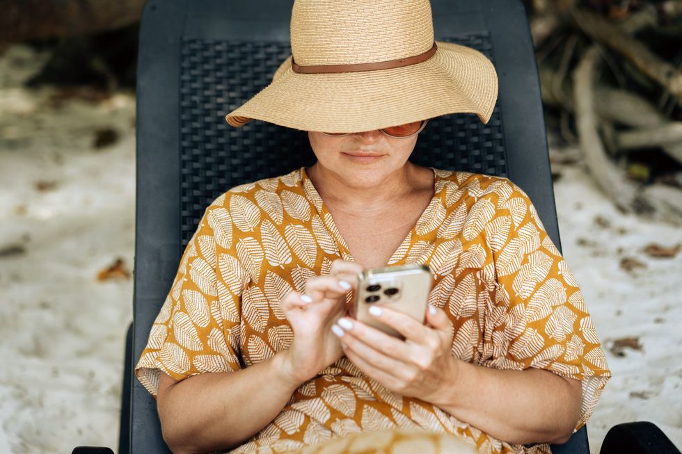 Woman sitting on the beach using her phone