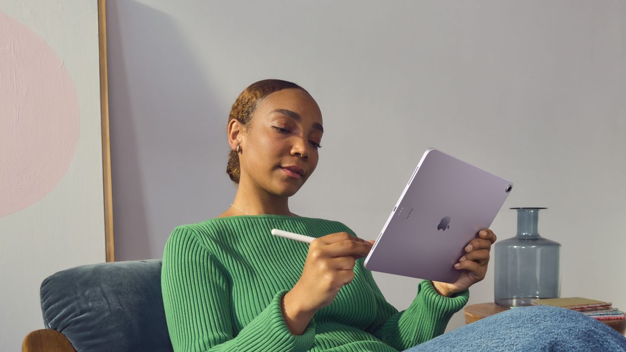 woman sitting reclined in a chair with the purple ipad air 2024 and an apple pencil stylus
