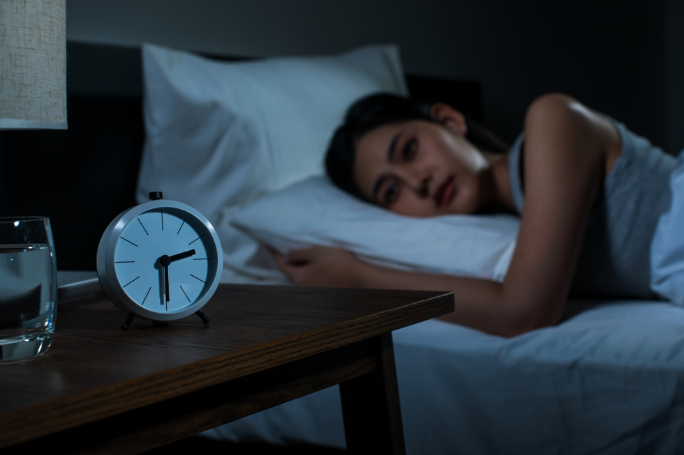 Woman struggling to sleep, looking at clock