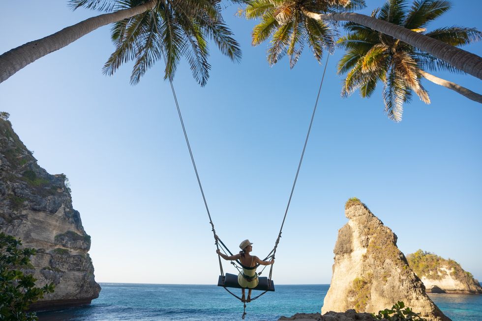 Woman swinging in Diamond Beach, Nusa Penida Bali, Indonesia