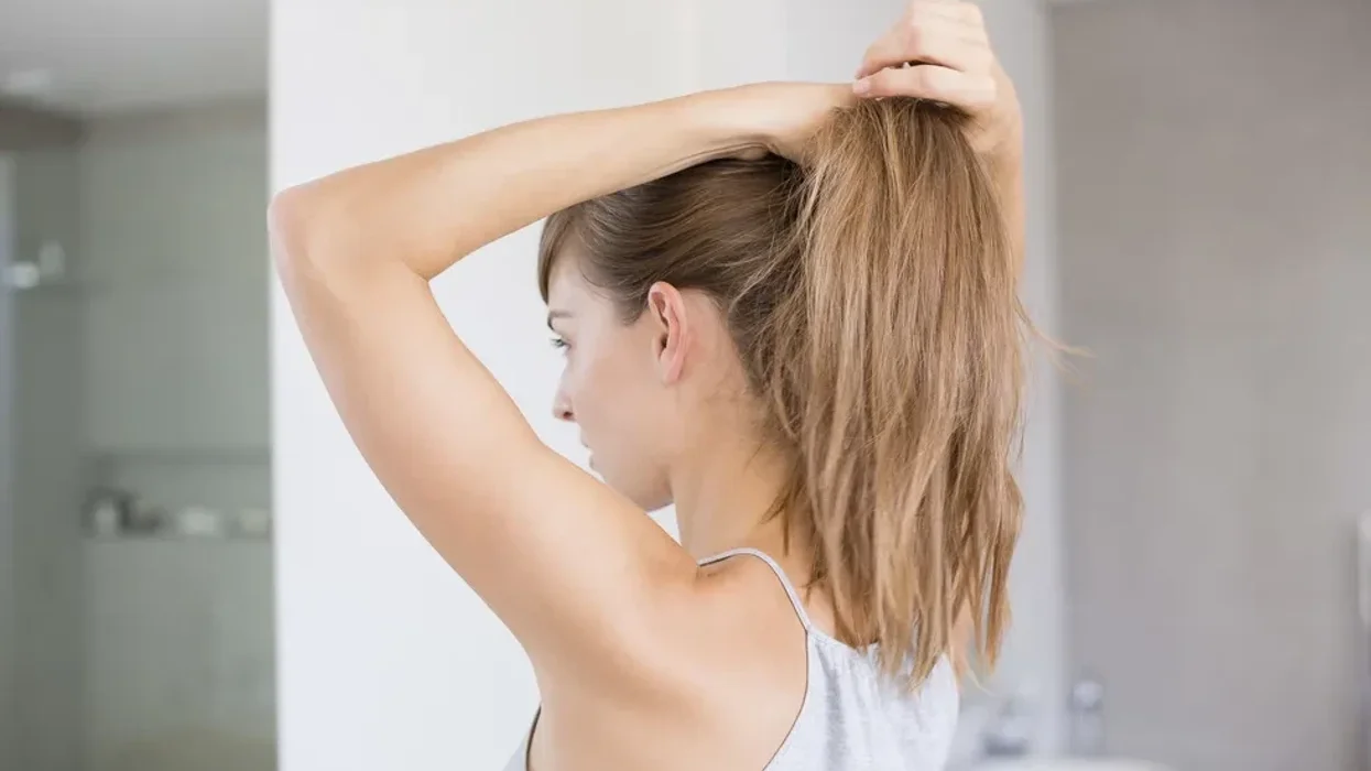 Woman tying her hair in a ponytail