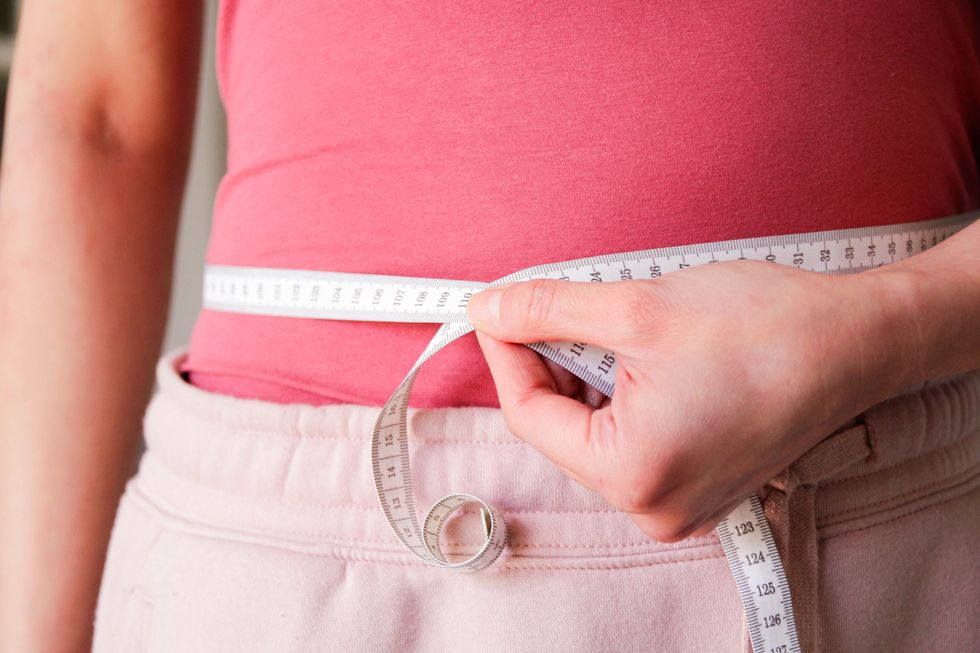Woman using a tape to measure her waist
