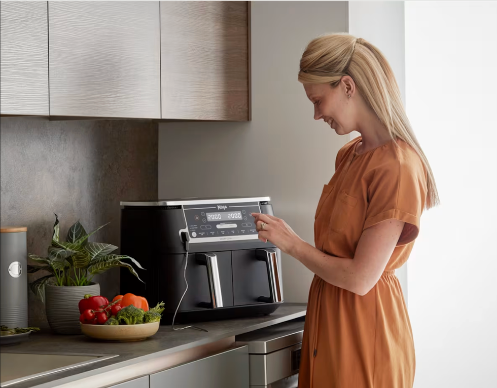 Woman using Ninja MAX 6-in-1 Dual Zone air fryer