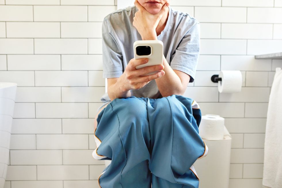 WOMAN USING PHONE ON TOILET
