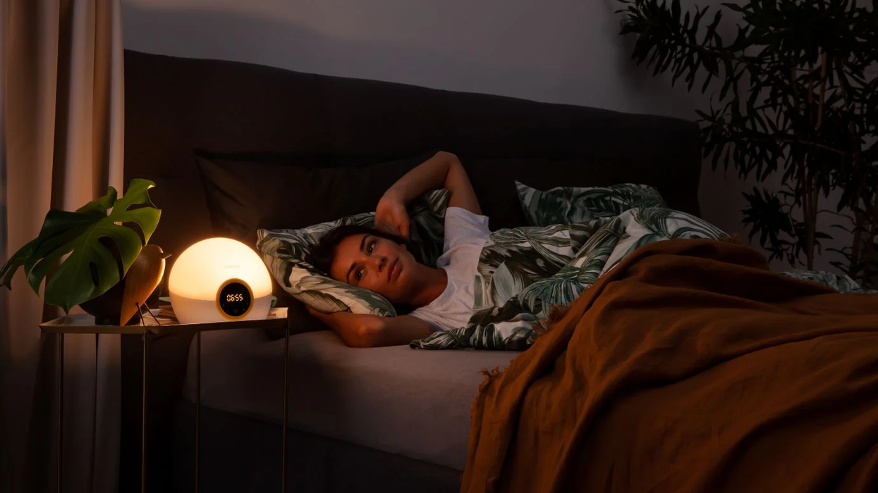 Woman waking up to the sunrise of the Lumie light alarm clock