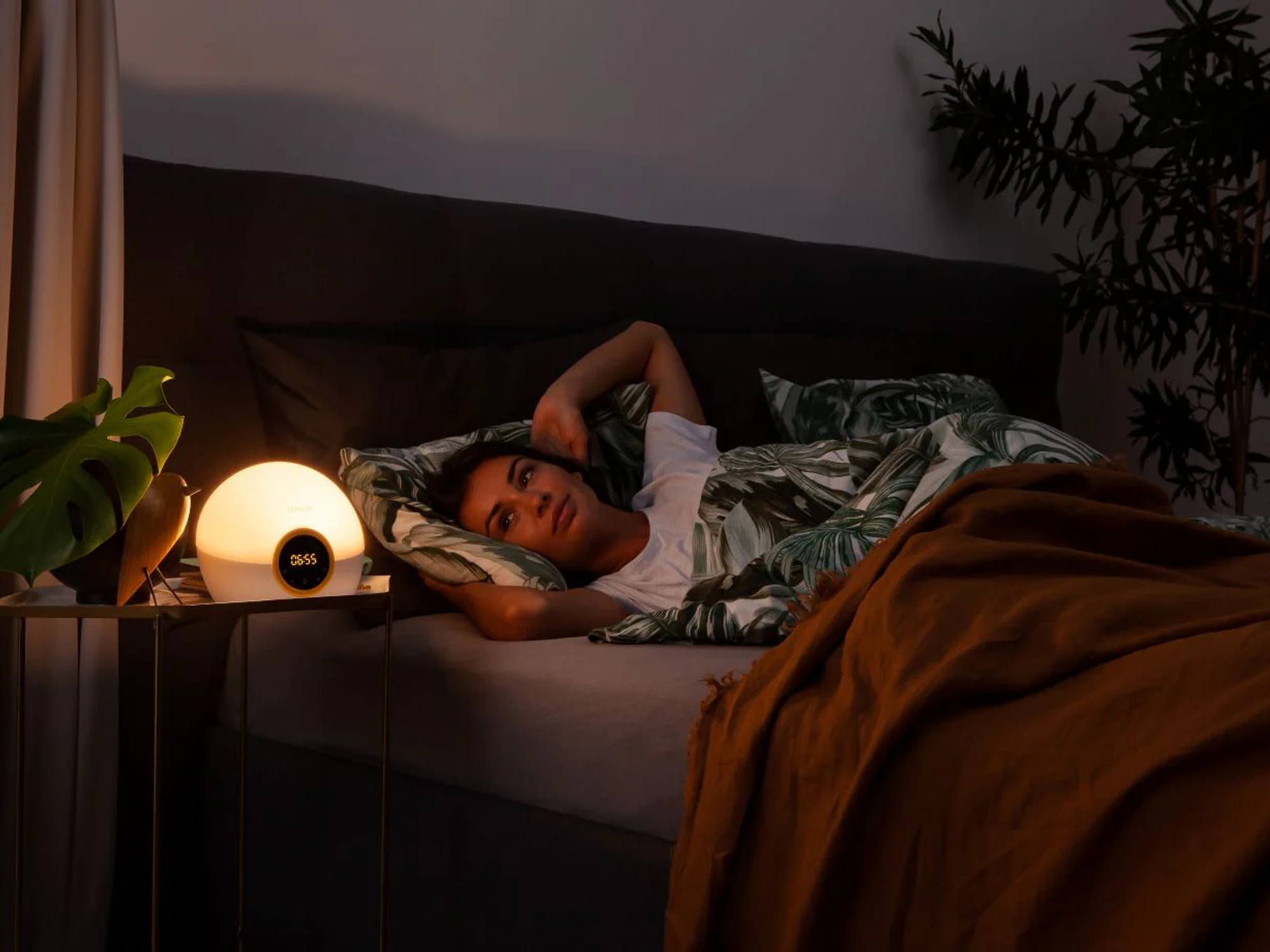 Woman waking up to the sunrise of the Lumie light alarm clock