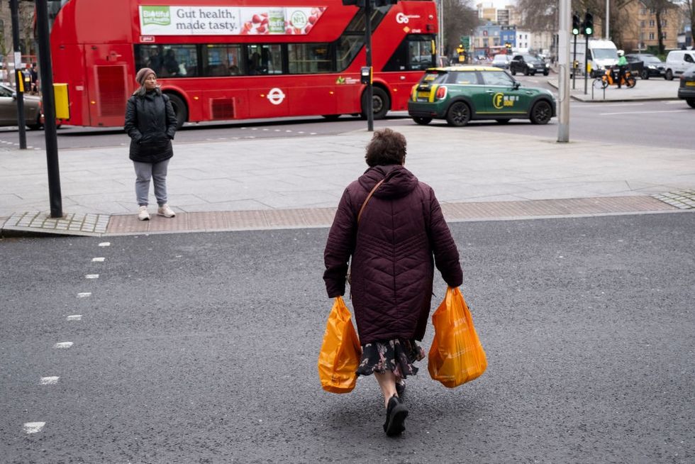 Woman walking across the street with sainsbury's bags