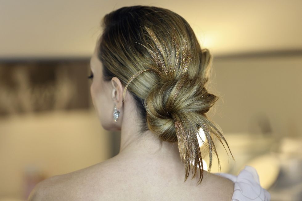 Woman wearing her hair in a bun with glitter streaks