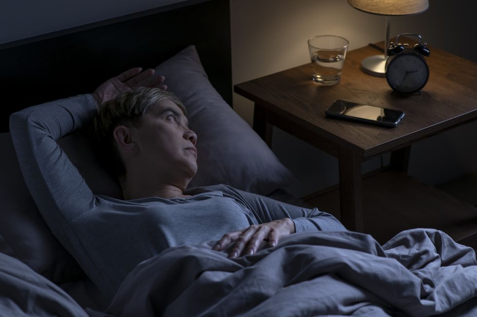 Woman who can't sleep looking at her alarm clock