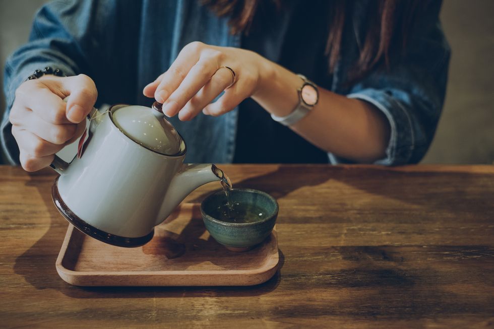 Woman with blue shirt pouring a cup of tea