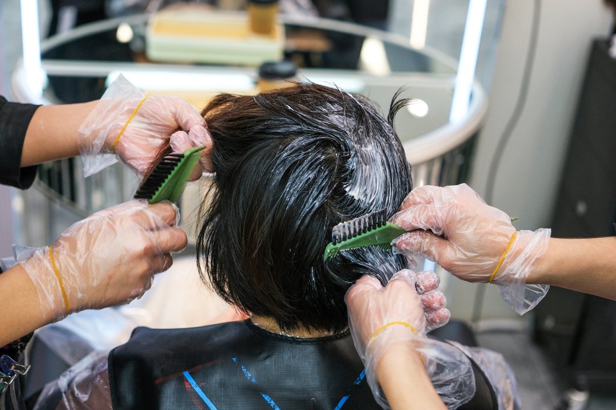 Woman with dark brown hair having it coloured in salon