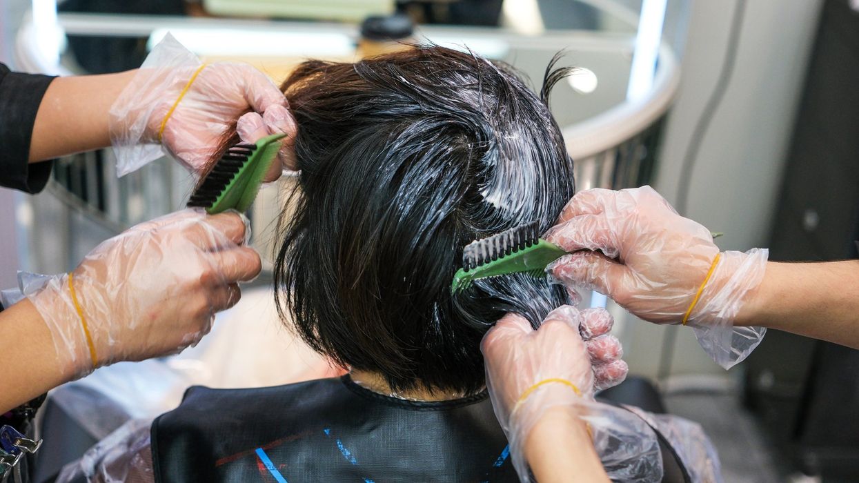 Woman with dark brown hair having it coloured in salon