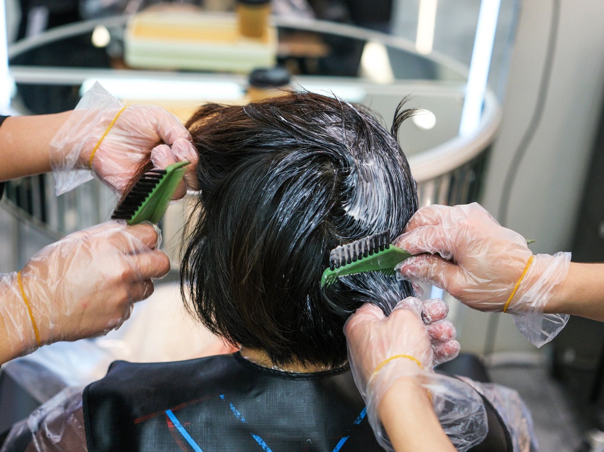 Woman with dark brown hair having it coloured in salon