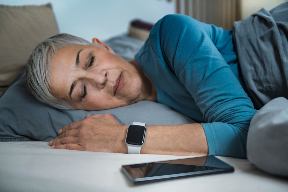 Woman with grey hair sleeping next to her phone