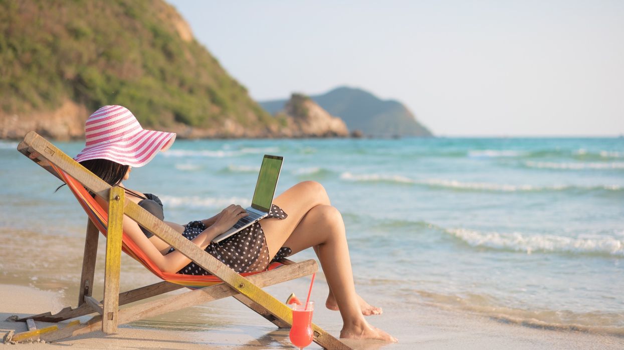 Woman working on her laptop on the beach