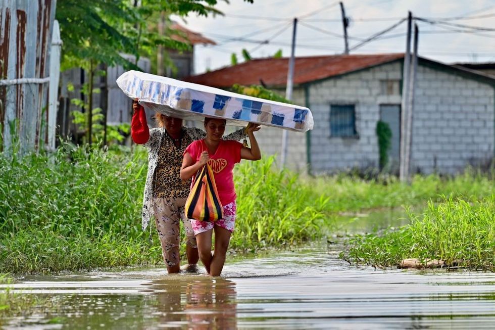 Women carry a mattress they received after floods in Yaguachi, Guayas Province