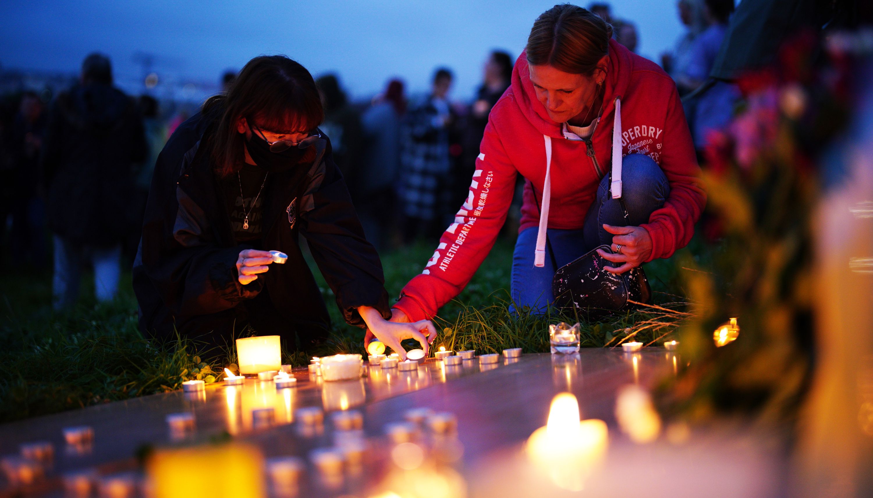 Women light candle at a vigil for the victims of the Keyham mass shooting at North Down Crescent Park in Keyham, Plymouth.
