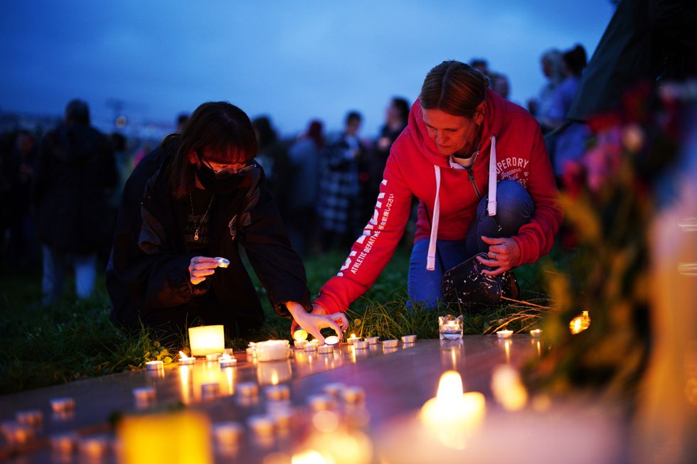 Women light candle at a vigil for the victims of the Keyham mass shooting at North Down Crescent Park in Keyham.