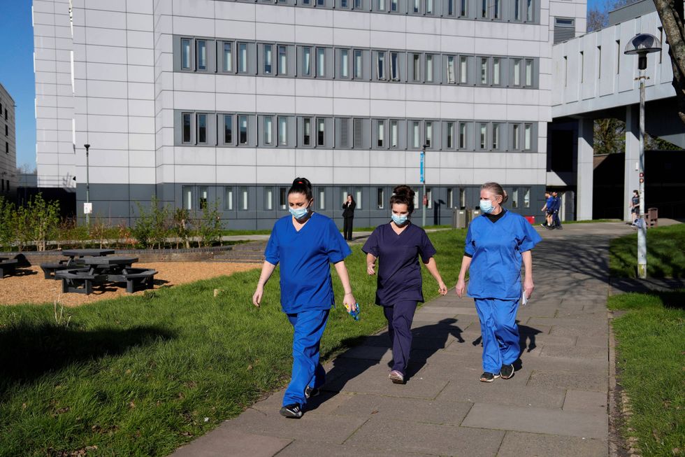 Women wearing scrubs walking in University of Kent plaza