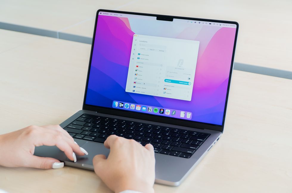 womens hands on a macbook with surfshark on-screen setting the current location for a vpn connection