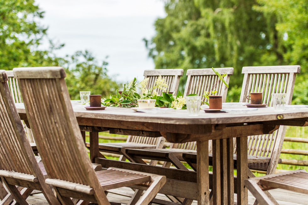 Wooden garden table and chairs, surrounded by greenery