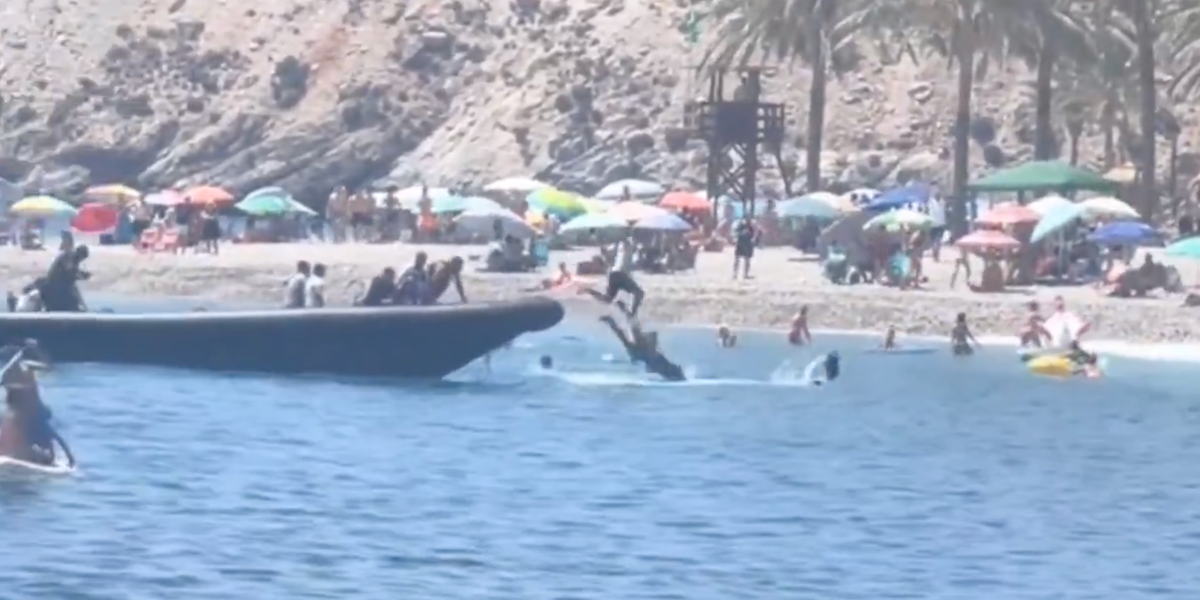 NextImg:Migrant tackled to floor after boat arrives at beach in British holiday hotspot