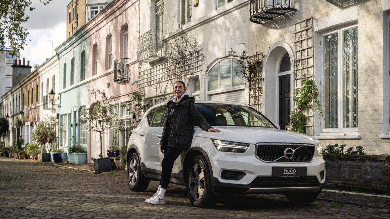 Xenia Muether stands in front of car with Turo number plate