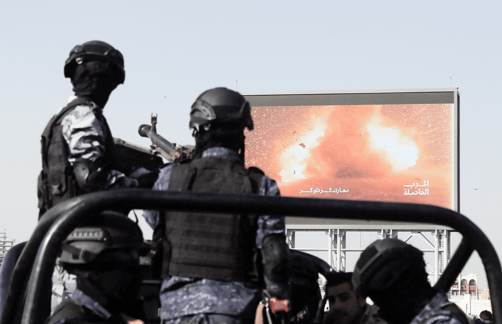 Yemen's Houthi forces ride a vehicle next to a large screen broadcasting an attack of Yemen's Houthis targeted a US battleship in the Red Sea, as they guard during a rally held to reject the plan of the US to oust the Palestinian people from Gaza, on February 14, 2025, in Sana'a, Yemen.