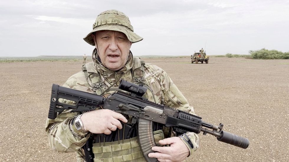 Yevgeny Prigozhin, chief of Russian private mercenary group Wagner, gives an address in camouflage and with a weapon in his hands in a desert area at an unknown location