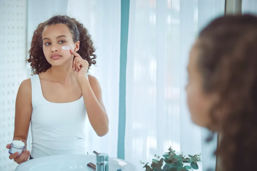 Young girl applying skincare