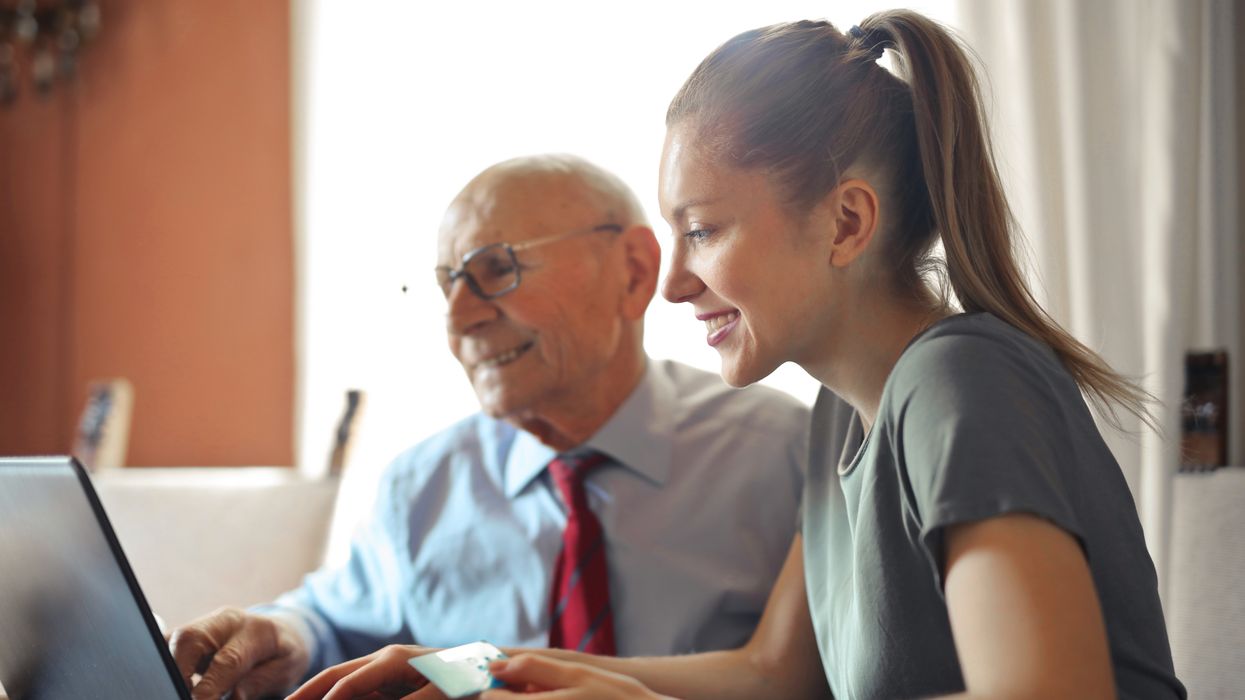 Young woman helping elderly man on a laptop