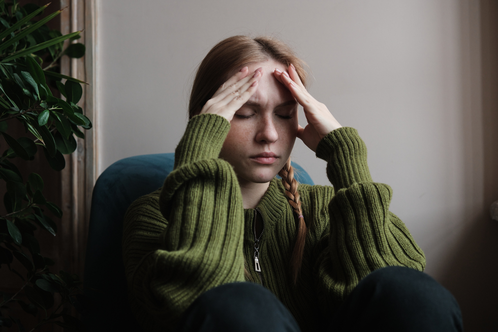 Young woman suffering from a migraine, holding her hands to her forehead