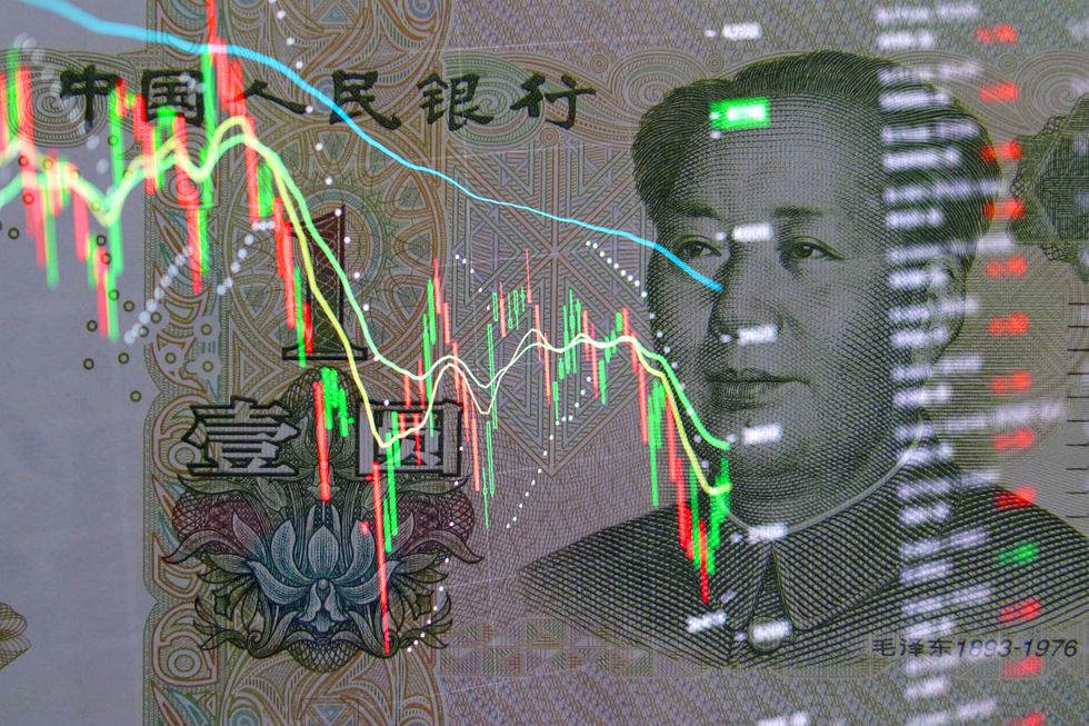 Yuan banknote on the background of stock charts